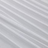 Przezroczyste, białe zasłony z ukośnymi fałdami, prawdopodobnie wykonane z poliestru pochodzącego z recyklingu, zapewniają prywatność, a jednocześnie przepuszczają światło.