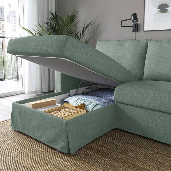 Zielona sofa z otwartym schowkiem, odsłaniającym koce i przekąski. Uggesties pod spodem.