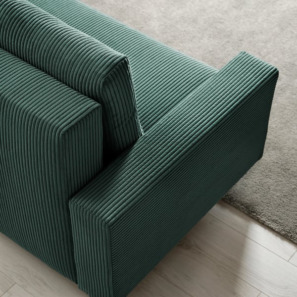 Zielona sofa z sztruksem z szezlongiem, schludny design, wygodne siedzenia i schowek pod spodem.