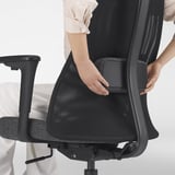 Regulowane podparcie lędźwiowe: pokazane ręce dostosowują podparcie oparcia na ergonomicznym krześle biurowym.