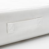 Zbliżenie na biały materac do łóżeczka, prezentujący wysokiej jakości szwy i detale z tkaniny.