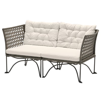 Nowoczesna wiklinowa sofa ogrodowa w kolorze szarym z białymi poduszkami.