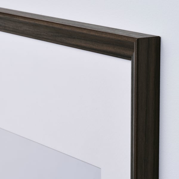 Zbliżenie minimalistycznej ramki na zdjęcia z eleganckim, ciemnym wykończeniem drewna i przezroczystą osłoną ochronną.