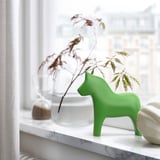 Jasnozielona ceramiczna figurka konia dala, mniejsza od wazonu, na marmurowej półce.