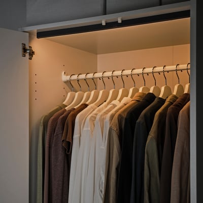 Szafa z ciepłymi paskami świetlnymi led, wieszanie ubrań na wieszakach, podświetlanie po otwarciu.