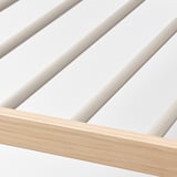 Zbliżenie na nowoczesny wieszak na spodnie z gładką, jasną drewnianą ramą i eleganckimi metalowymi prętami.