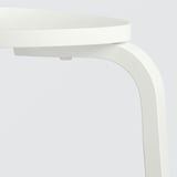 Biały stołek na 3 nogach, starannie ułożony, prezentujący solidny design i gładkie wykończenie.