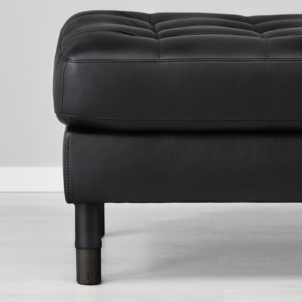 Meble tapicerowane w kolorze czarnej skóry z drewnianymi nogami; Zbliżenie detalu pokazujące wysokiej jakości szwy i fakturę materiału.