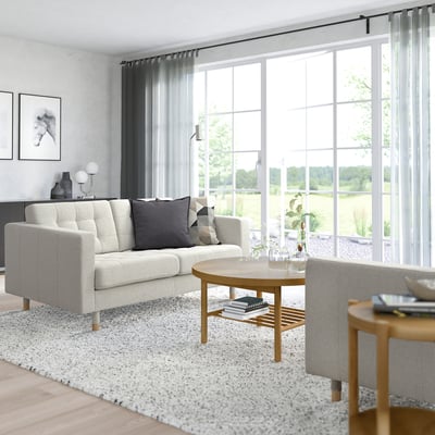 Nowoczesny salon z sofą LANDSKRONA, stolikiem kawowym i dużymi oknami.