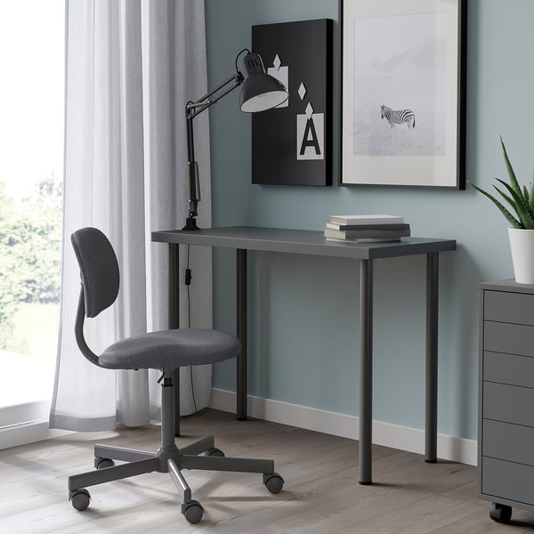 Nowoczesne szare biurko LINNMON z metalowymi nogami, krzesłem biurowym, książkami i wydrukami artystycznymi.