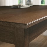 Stół do jadalni z ciemnego drewna z elegancką, fazowaną krawędzią, świadczący o kunszcie wykonania i solidnym designie.