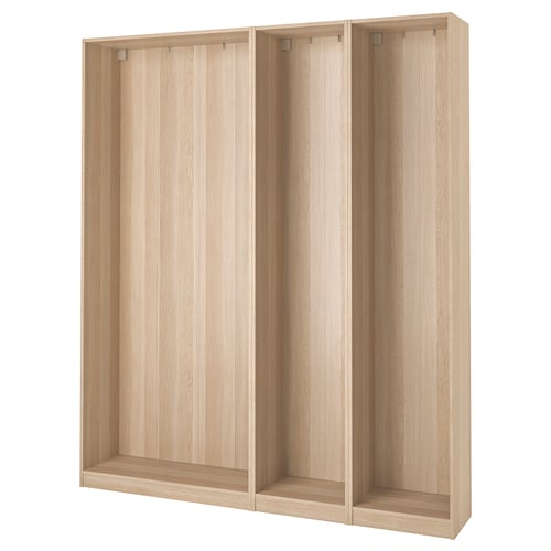 Rama szafy ikea PAX w kolorze jasnego drewna. Jest wysoki i prostokątny z regulowanymi nóżkami, przeznaczony do przechowywania w sypialni.