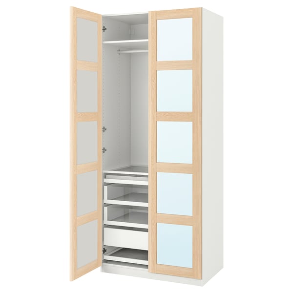 Otwarta biała szafa PAX z akcentami z jasnego drewna. Szklane drzwi, szuflady, półki i miejsce do zawieszania.