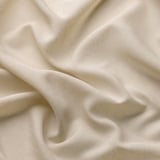 Miękka, beżowa, przezroczysta zasłona elegancko się składa; Wykonane z poliestru pochodzącego z recyklingu, zapewnia prywatność, a jednocześnie pozwala na delikatne światło.