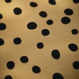 Prześcieradło z gumką w groszki w złotym kolorze, gładka faktura, równomiernie rozmieszczone czarne kropki.