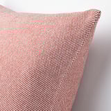 Czerwono-biała poduszka z tkaną fakturą, umieszczona na białej powierzchni. Pokrowiec posiada szczegółowy, przyjemny w dotyku wzór.