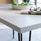 Nowoczesny metalowy stół jadalny z zielonymi jabłkami i gazetami. Alternatywna krótsza wersja: metalowy stół jadalny z owocami i gazetami.