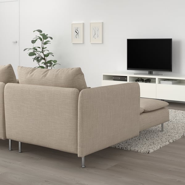 Nowoczesna beżowa sofa segmentowa z szezlongiem, białą ścianą, szafką RTV, rośliną.