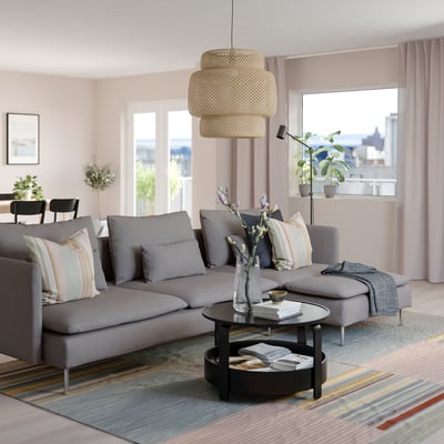 Nowoczesny salon: szara sofa segmentowa SÖDERHAMN, poduszki w paski, okrągły stolik kawowy, stylowa lampa wisząca, duże okno z widokiem na miasto.