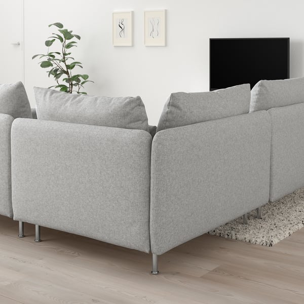 Biało-szara sofa SÖDERHAMN, nowoczesny niski profil, przestronne poduszki, eleganckie metalowe nogi, duży telewizor, roślina, minimalistyczna sztuka, przytulny dywan, jasny, przestronny pokój.