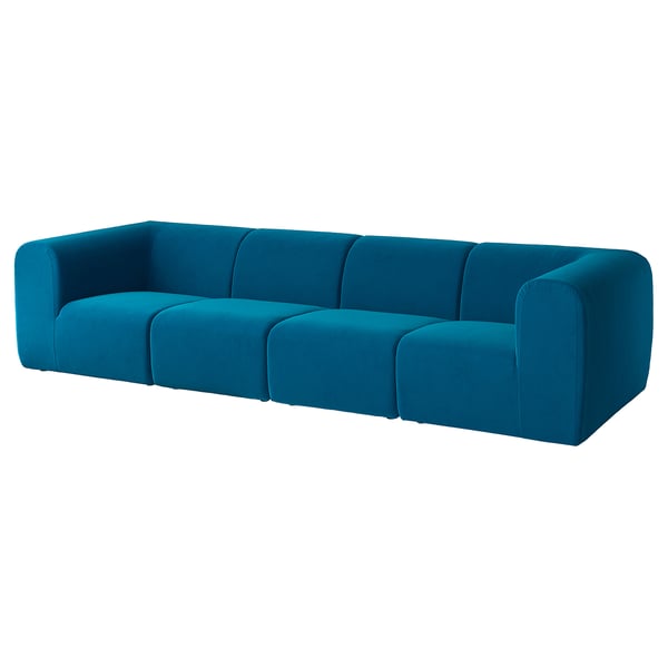 Niebieska aksamitna sofa, nowoczesny design, miękkie krzywizny, trzy poduszki, stylowy element centralny.