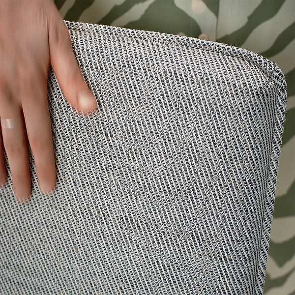 Ręka trzymająca próbkę szarej teksturowanej tkaniny, prezentująca jej miękki, trwały splot o lekkiej fakturze, idealny do pokrowców na meble.