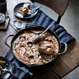 Żeliwna patelnia z ciastem na drewnianym stole. Talerz z kawałkiem ciasta, łyżką i sztućcami w pobliżu.