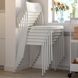 Stos białych krzeseł VIHALS starannie przechowywany. Minimalistyczny design, odpowiedni do użytku w pomieszczeniach, łatwy do przenoszenia i czyszczenia.