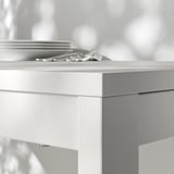 Zbliżenie na nowoczesny, minimalistyczny stół jadalny z eleganckimi, białymi krawędziami i gładkimi powierzchniami, podkreślający jego czysty design i solidną konstrukcję.