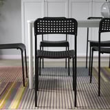 Stackable indoor plastic chairs in black, arranged on a striped rug.