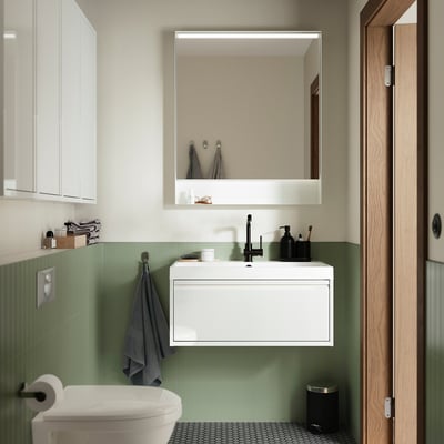 Modern minimalist bathroom unit, wall-mounted with green tiles, sink, mirror, toilet, and black accents.