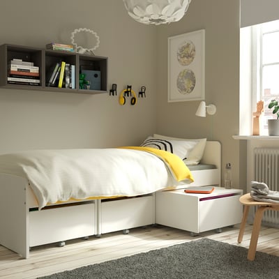 Modern bedroom with ÄRENDE grey rug, white bed, shelves, and wall art.
