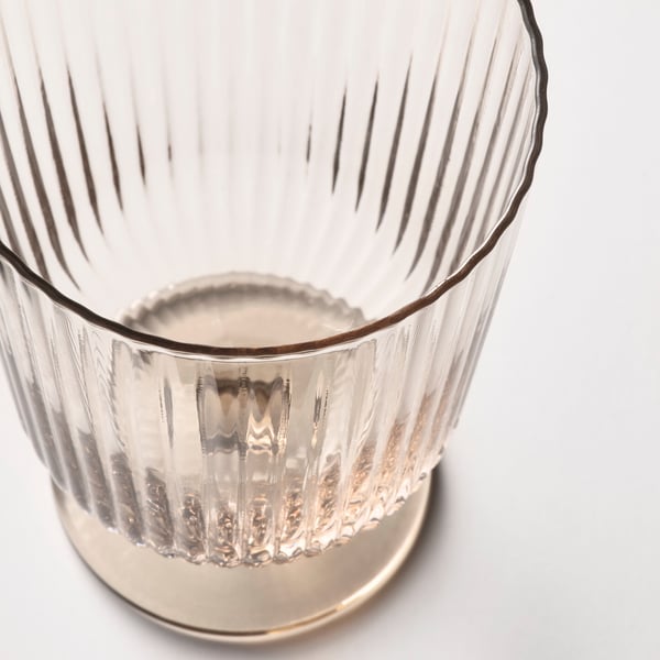 Translucent, ribbed glass cup with a textured base, captured from an upward angle against a white background.