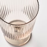 Translucent, ribbed glass cup with a textured base, captured from an upward angle against a white background.