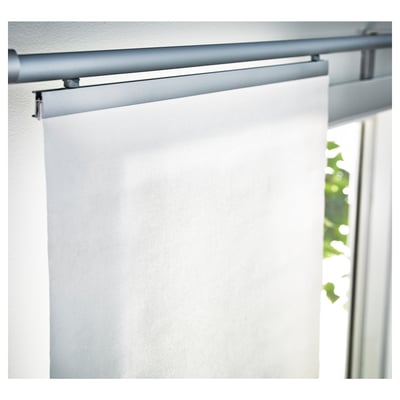 White roller blind partially rolled up, mounted on a minimalist silver track above a window. Lightly filters outside light.