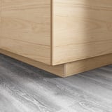 Wooden kitchen cabinets with smooth, easy-clean finish. They meet gray wood-patterned floor, creating modern look.