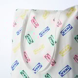 White cotton tote bag with colorful ikea logos scattered across fabric, thick handles for carrying, ideal for shopping or casual use.