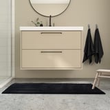 Modern bathroom with light beige BACKMÅRA mat, black towels, and floating vanity.