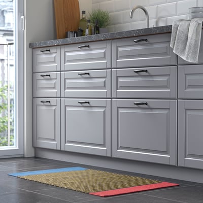 Modern kitchen grey cabinets, marble countertop, and a colourful striped rug in front, providing a vibrant touch to the sleek design.