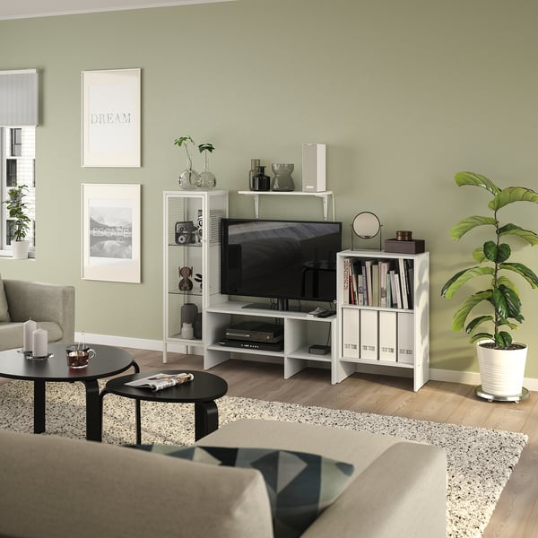 Contemporary living room with green walls, l-couch, black coffee table, tv, books, decor, and wall art.