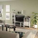 Contemporary living room with green walls, l-couch, black coffee table, tv, books, decor, and wall art.