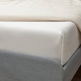 Bed with white organic cotton sheet; breathes, soft, easy-care, certified gots.