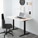 Minimalist home office with white BEKANT desk, black chair, laptop, lamp, and wall organizer.