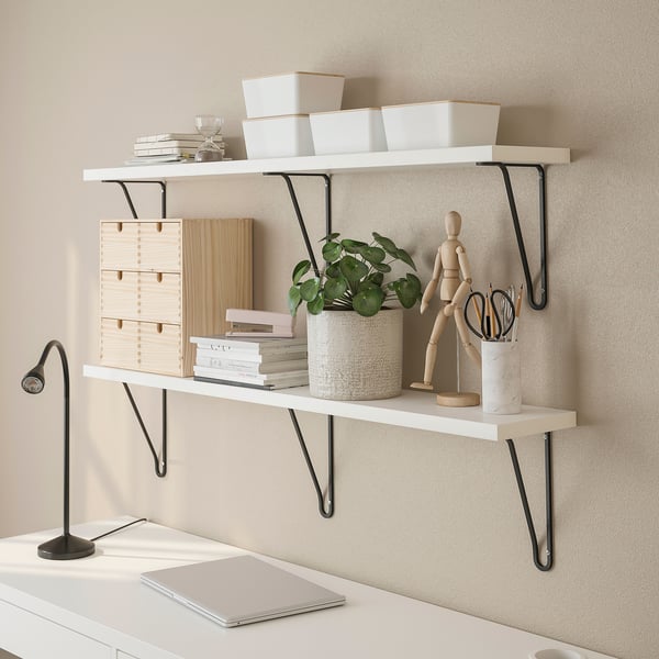 Shelves with black brackets, boxes, papers, plant, and laptop below.
