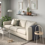 Modern living room with BERGSHULT white wall shelf and couch. Decorated with framed art and plants.