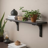 Wall-mounted shelf holding books, plants, and decor. Displays items neatly and utilizes wall space.