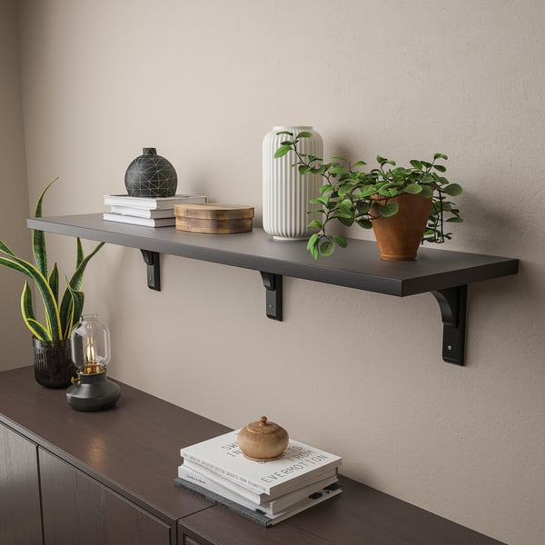 Wall shelf with black brackets holds decorative items like plants, books, and vases.