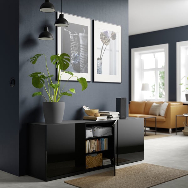 Modern living room with black BESTÅ sideboard, books, basket, plant, and art.