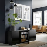 Modern living room with black BESTÅ sideboard, books, basket, plant, and art.