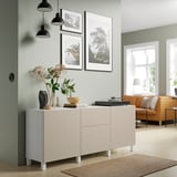 White BESTÅ sideboard in living room with drawers, shelves, orange sofa, lights, wood floors, rug.